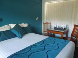 a bedroom with a bed and a desk at Moore Park Beach Motel in North Coast