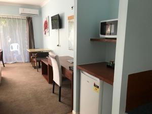 a kitchen and dining room with a table and a microwave at Springwood Motor Inn in Springwood