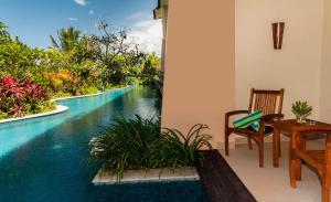 Una casa con mesa y silla y vistas a la piscina en The Natsepa Resort and Conference Center, en Ambon