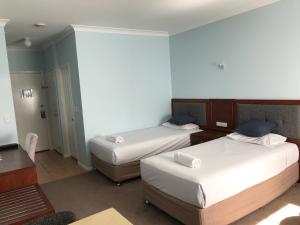 a hotel room with two beds and a desk at Springwood Motor Inn in Springwood