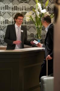 Twee mannen in pakken staan aan de balie. bij The Originals City, Hôtel Astoria Vatican, Lourdes (Inter-Hotel) in Lourdes