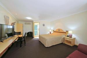 a hotel room with a bed and a desk and a tv at Villa Mirasol Motor Inn in Bundaberg