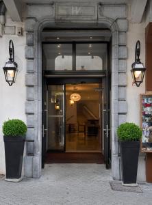 une entrée à un bâtiment avec deux plantes en pot dans l'établissement The Originals City, Hôtel Astoria Vatican, Lourdes (Inter-Hotel), à Lourdes