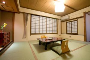 Zimmer mit einem Tisch, Stühlen und Fenstern in der Unterkunft Onyado Tsutaya in Kiso