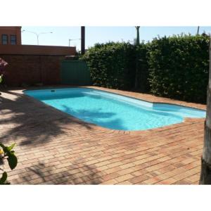 a small swimming pool on a brick patio at Yambil Inn in Griffith