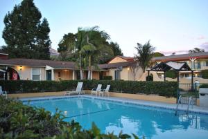 a swimming pool in front of a house with two chairs at Oasis Inn and Suites in Santa Barbara