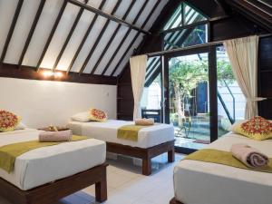 um quarto com 3 camas e uma grande janela em Gili Turtle Beach Resort em Gili Trawangan