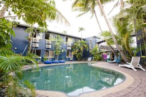 a swimming pool in front of a building with palm trees at Mad Monkey Village in Cairns