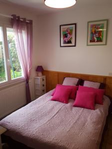 una camera da letto con un letto con cuscini rosa e una finestra di Holiday Home Filie a Andernos-les-Bains