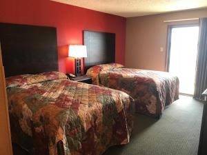 two beds in a hotel room with red walls at D’Arbonne Lake Motel in Farmerville