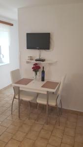 a dining room table and chairs with a tv on the wall at Apartman Duba in Senj