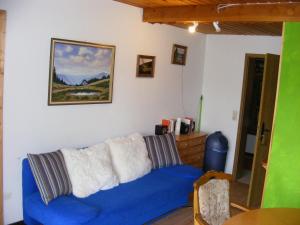 eine blaue Couch in einem Wohnzimmer mit einem Gemälde in der Unterkunft Appartementhaus Schwarzwaldblick in Lauterbach