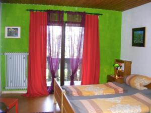 a bedroom with two beds and red curtains at Appartementhaus Schwarzwaldblick in Lauterbach