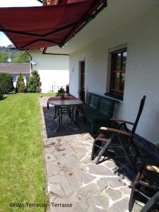 une terrasse avec une table, des chaises et un parasol dans l'établissement Haus Ellerbeck, à Bodenmais