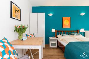 1 dormitorio con pared azul, cama y mesa en OLECKI Holiday Haus, en Dźwirzyno