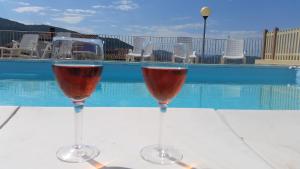two glasses of wine sitting on a table next to a pool at Casa vacanze "La Caldosa" in Badesi