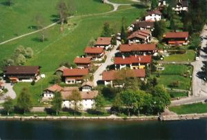 um grupo de casas numa colina junto à água em Wohnung Edelweiß - Wohnen auf Zeit - Homeoffice - nah am See - buchbar ab 28 Nächte em Schliersee