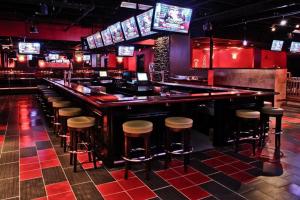 a bar with stools in a room with televisions at Ramada by Wyndham Rochelle Park Near Paramus in Rochelle Park