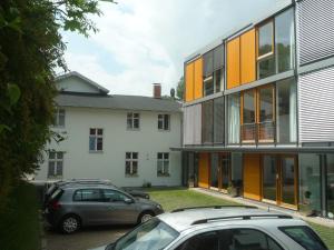 Dos coches estacionados en un estacionamiento frente a un edificio. en Mini-Reihenhaus "Alte Buchdruckerei", en Heringsdorf