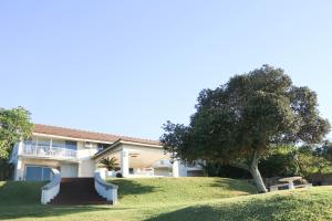 a large house with a tree in front of it at The Milkwood Beach Apartments in Amanzimtoti