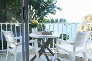 a white table and chairs on a balcony at The Milkwood Beach Apartments in Amanzimtoti