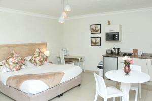 a bedroom with a bed and a table and a kitchen at The Milkwood Beach Apartments in Amanzimtoti