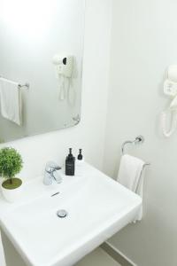 a white bathroom with a sink and a mirror at The Milkwood Beach Apartments in Amanzimtoti