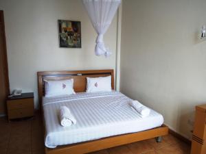 a bedroom with a bed with white sheets and pillows at Aponye Hotel Kampala in Kampala