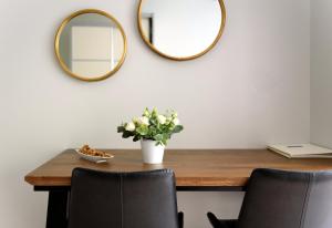 a table with a vase of flowers and two mirrors at Sea Land Suites in Tel Aviv
