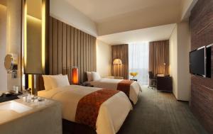 PO Hotel Semarang في سيمارانغ: غرفه فندقيه سريرين وتلفزيون
