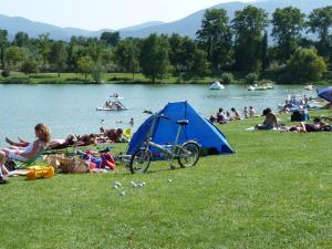 a group of people sitting on the grass near a lake at Maison MICDEN in Saint-Jean-Pla-de-Corts
