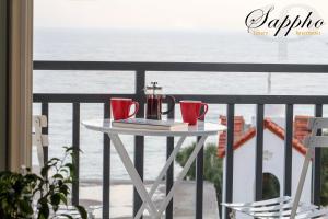 a table with two red cups on a balcony with the ocean at Sappho Plomari in Plomarion