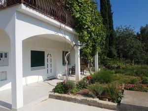 ein weißes Gebäude mit einem Torbogen neben einem Garten in der Unterkunft Apartment Okrug Gornji - Trogir with Sea View in Trogir