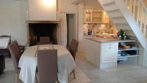 a kitchen and a dining room with a table and a staircase at Le Cèdre enchanté in La Guiche