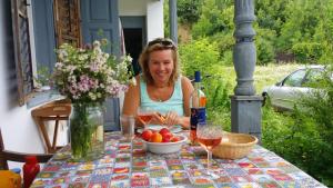 a woman sitting at a table with a bowl of fruit at Komfortcaravan in Kalaznó