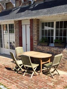 een houten tafel en stoelen voor een bakstenen huis bij L’annexe in Villers-sur-Mer