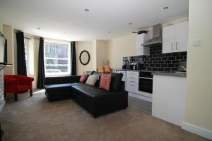 a living room with a black couch and a kitchen at Stafford apartments in Stafford