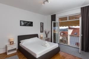 a white bedroom with a bed and a balcony at Apartments Green Scenic in Dubrovnik