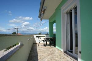 a balcony of a house with a table and chairs at Lucija Apartments in Krk