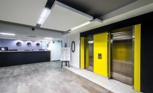 een kantoorlobby met gele deuren en een balie bij Aramis in Warschau