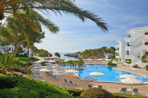 a beach scene with a pool and a large building at Inturotel Esmeralda Park in Cala d´Or