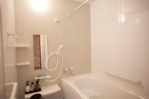 a white bathroom with a tub and a toilet at Oyama TABI-NE in Kanazawa