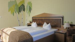 a bedroom with a bed with white sheets and a tree mural at Hotel Zum Leineweber in Burg