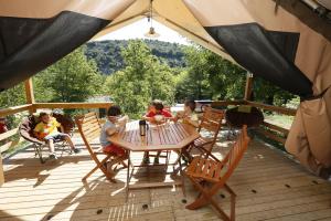 un groupe d'enfants assis autour d'une table sur une terrasse dans l'établissement camping aloha plage, à Sampzon