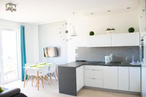 a kitchen with white cabinets and a table with chairs at Grey & White Pogodne in Kołobrzeg