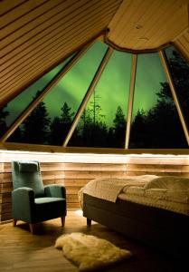 una camera da letto con una grande finestra con un letto e una sedia di Wilderness Hotel Inari & Igloos a Inari