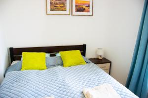 a bedroom with a bed with two yellow pillows at Grey & White Pogodne in Kołobrzeg