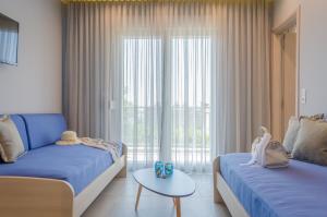 a bedroom with two beds and a table in front of a window at GiRene Apartments in Limenaria