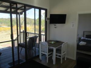 een kamer met een tafel en stoelen en een balkon bij Just Red Wines Cabins in Ballandean