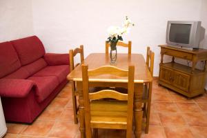 sala de estar con mesa y sofá rojo en Villa la Dehesa, en Conil de la Frontera
